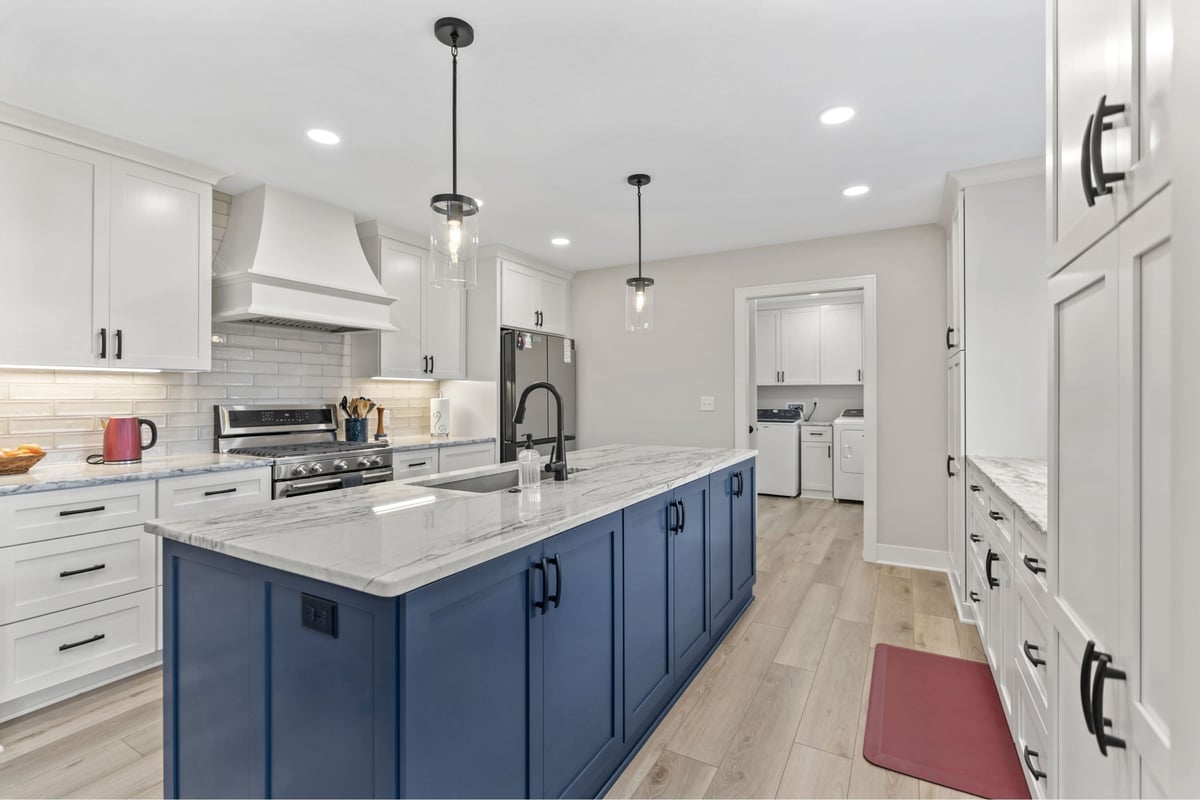 Custom kitchen remodel in Stilwell, KS with blue island, white cabinets, stainless appliances, and access to the laundry room.