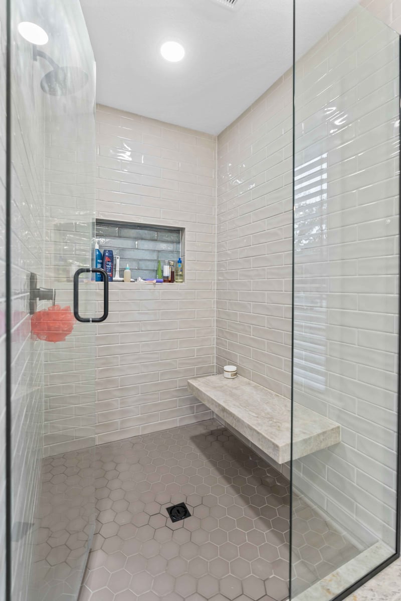 Custom walk-in shower in Stilwell, KS with tile walls, built-in bench, niche shelving, and hex tile floor.