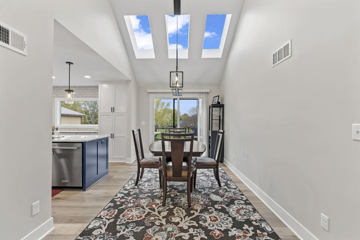 Dining area remodel in Stilwell, KS with skylights, modern lighting, new flooring, and access to the outdoor deck.