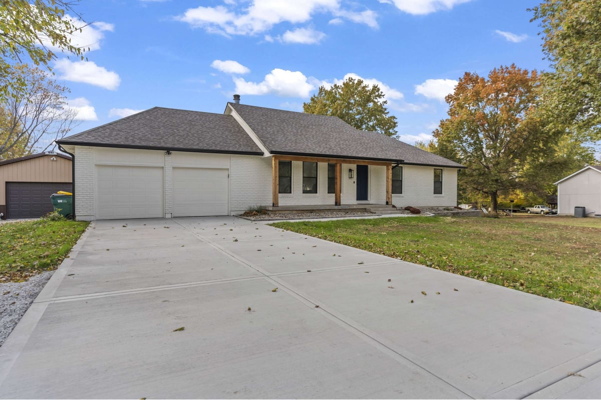 Exterior view of remodeled home in Stilwell, KS with new driveway, updated landscaping, and refreshed front porch.