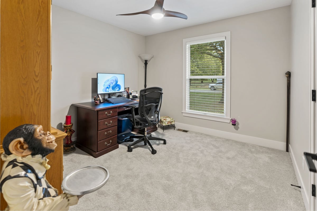 Home office remodel in Stilwell, KS featuring new carpet, modern ceiling fan, and natural light from updated windows.