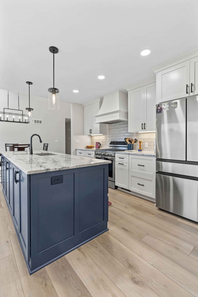 Modern kitchen remodel in Stilwell, KS with stainless steel range, white cabinets, quartz counters, and blue island centerpiece.