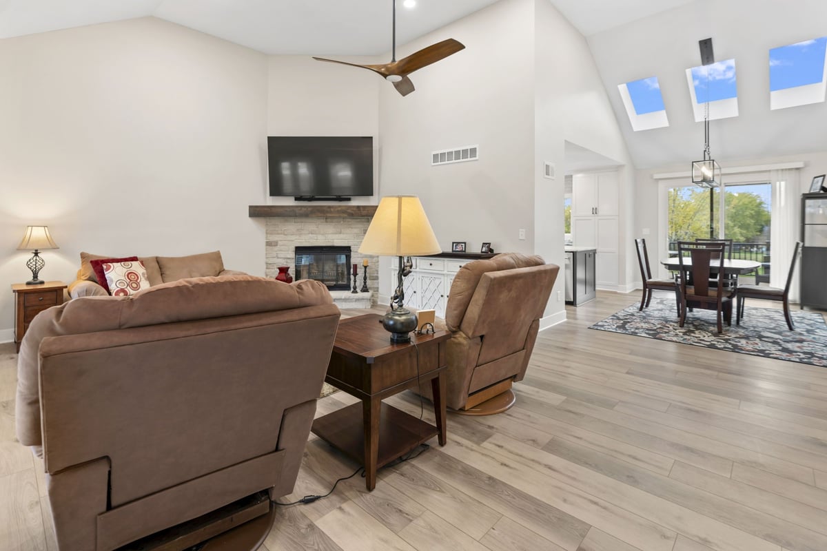 Open-concept living room remodel in Stilwell, KS with vaulted ceilings, new flooring, fireplace, and sightlines into the kitchen and dining area.