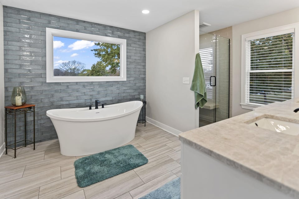 Primary bathroom remodel in Stilwell, KS featuring freestanding tub, glass shower enclosure, and tile flooring.