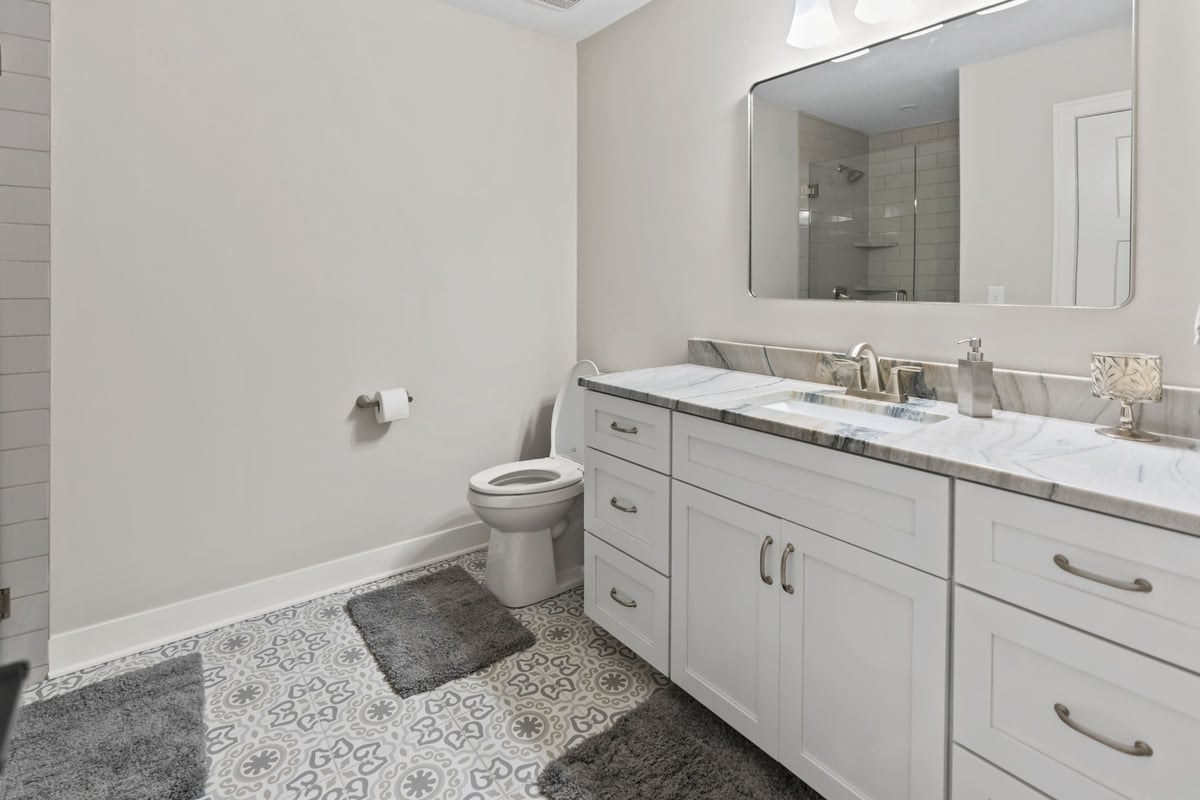 Primary bathroom remodel in Stilwell, KS with custom white vanity, quartz countertop, modern fixtures, and patterned tile floor.