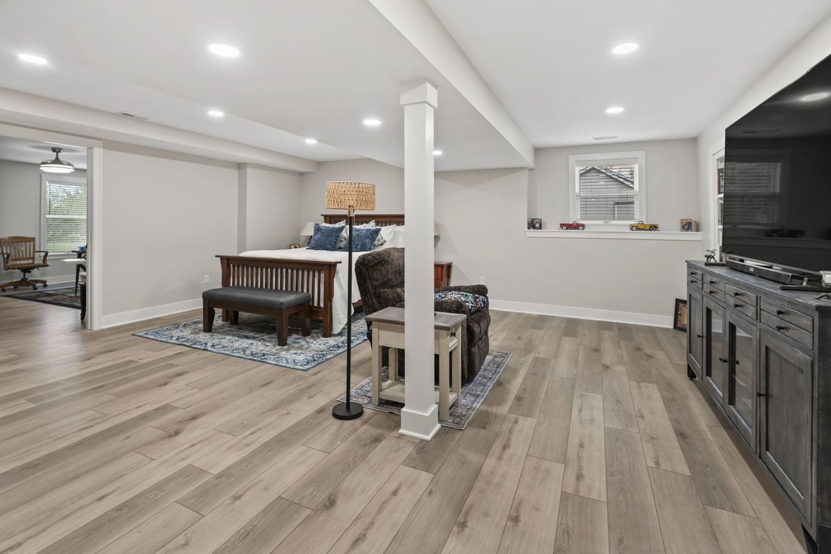 Remodeled basement living space in Stilwell, KS featuring new flooring, recessed lights, and open layout for seating and media.