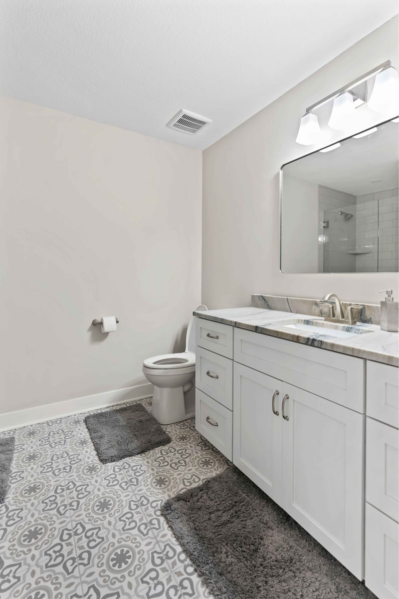 Updated bathroom vanity in Stilwell, KS featuring quartz counters, framed mirror, modern lighting, and custom cabinetry.