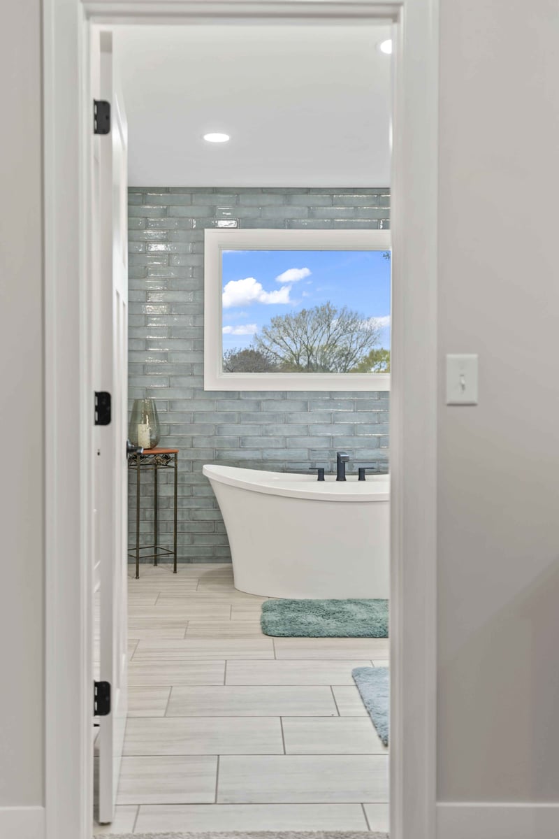 View from primary bedroom into ensuite bathroom in Stilwell, KS featuring blue tile accent wall and freestanding tub.