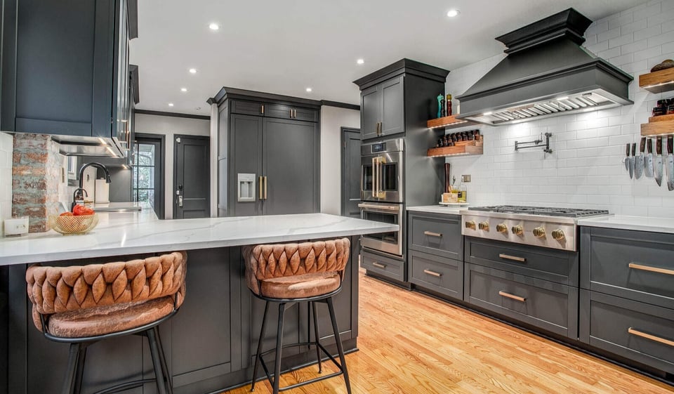 Elegant kitchen remodel featuring a marble countertop island, dark cabinetry, and wood flooring in Waldo, MO