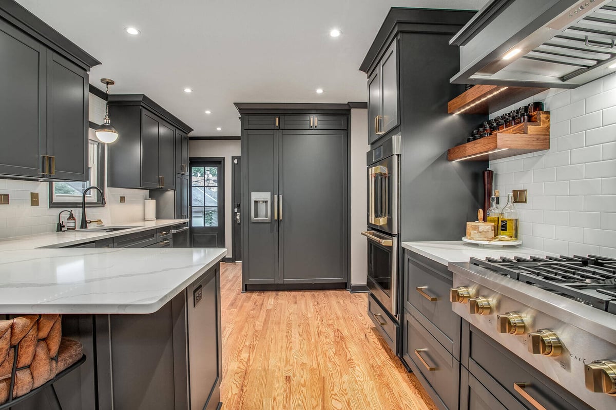 Modern kitchen renovation with a spacious island, dark cabinets, and warm wood floors by Top Shelf Home Builders