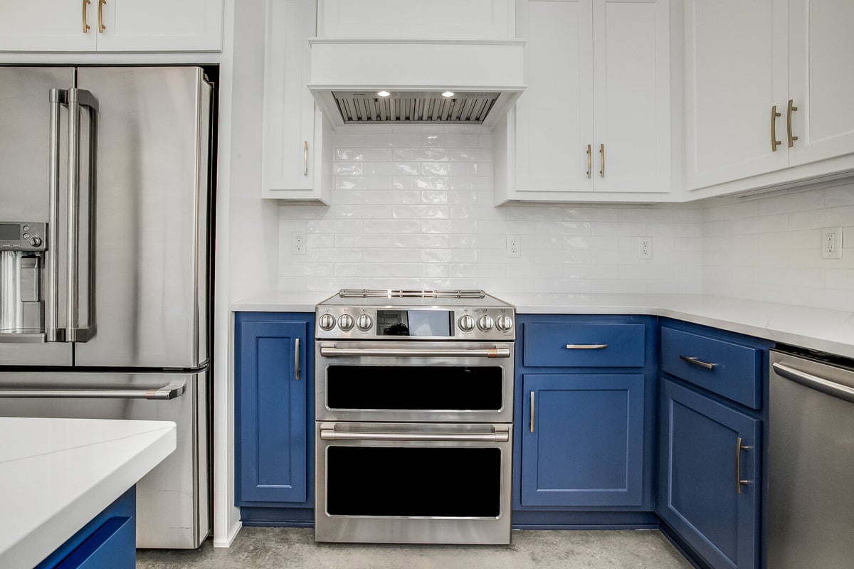 Close-up of a modern stainless steel double oven and range hood, part of a whole home remodel by Top Shelf Home Builders in Metro Kansas City