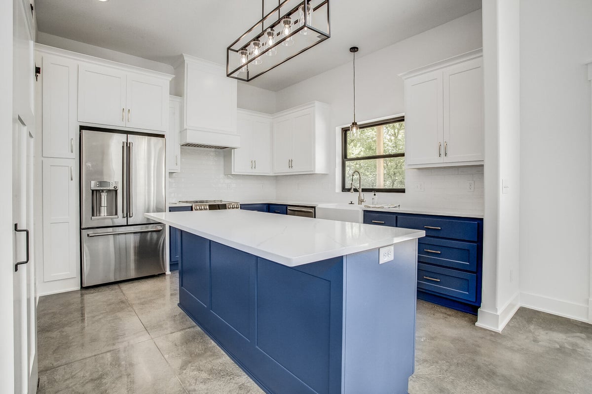 Contemporary kitchen featuring a spacious island, white upper cabinets, and blue lower cabinets, part of a whole home remodel in Metro Kansas City