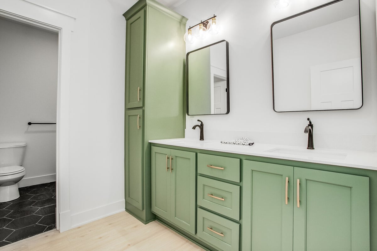 Elegant bathroom with green double vanity, white countertops, and black fixtures in a Kansas City home remodel by Top Shelf Home Builders