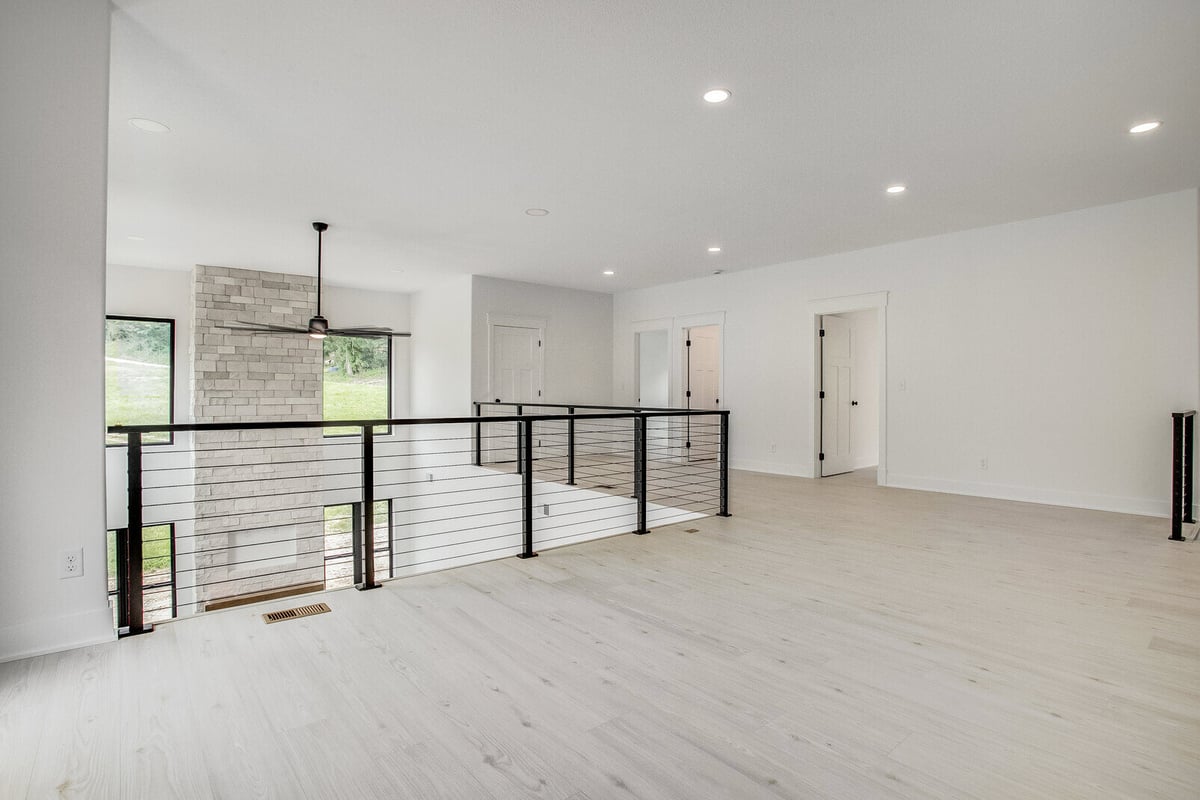 Light-filled open loft space with cable railing and brick column in a Kansas City home remodel by Top Shelf Home Builders