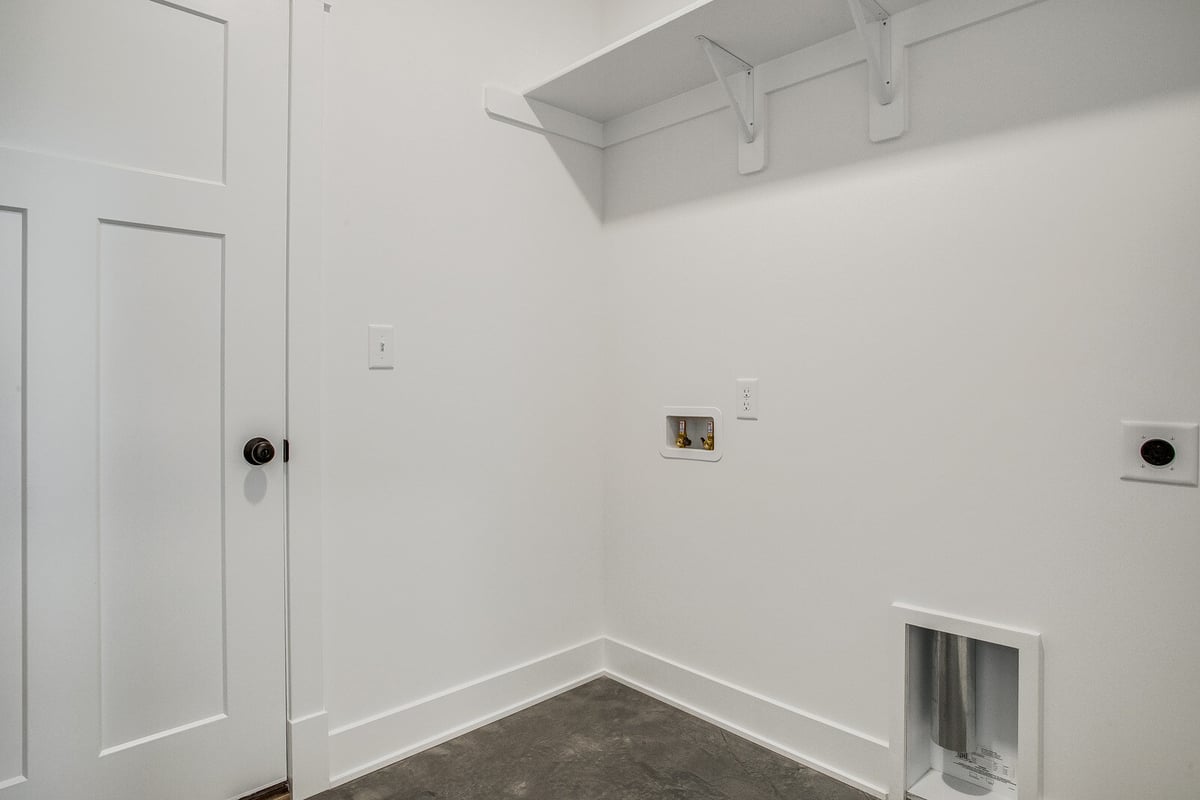 Modern laundry room with a bright white finish, featuring washer and dryer hookups, part of a Metro Kansas City home remodel by Top Shelf Home Builders.jpg