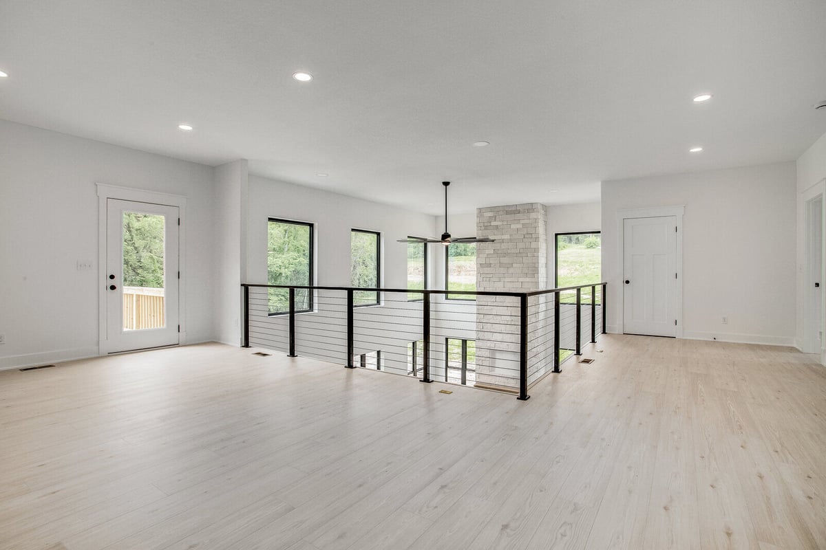 Open-concept upper-level living space with modern railing and large windows in a Metro Kansas City home remodel by Top Shelf Home Builders