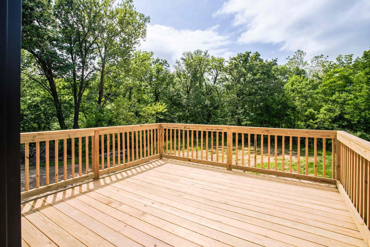 Outdoor wooden deck with natural railing overlooking lush greenery