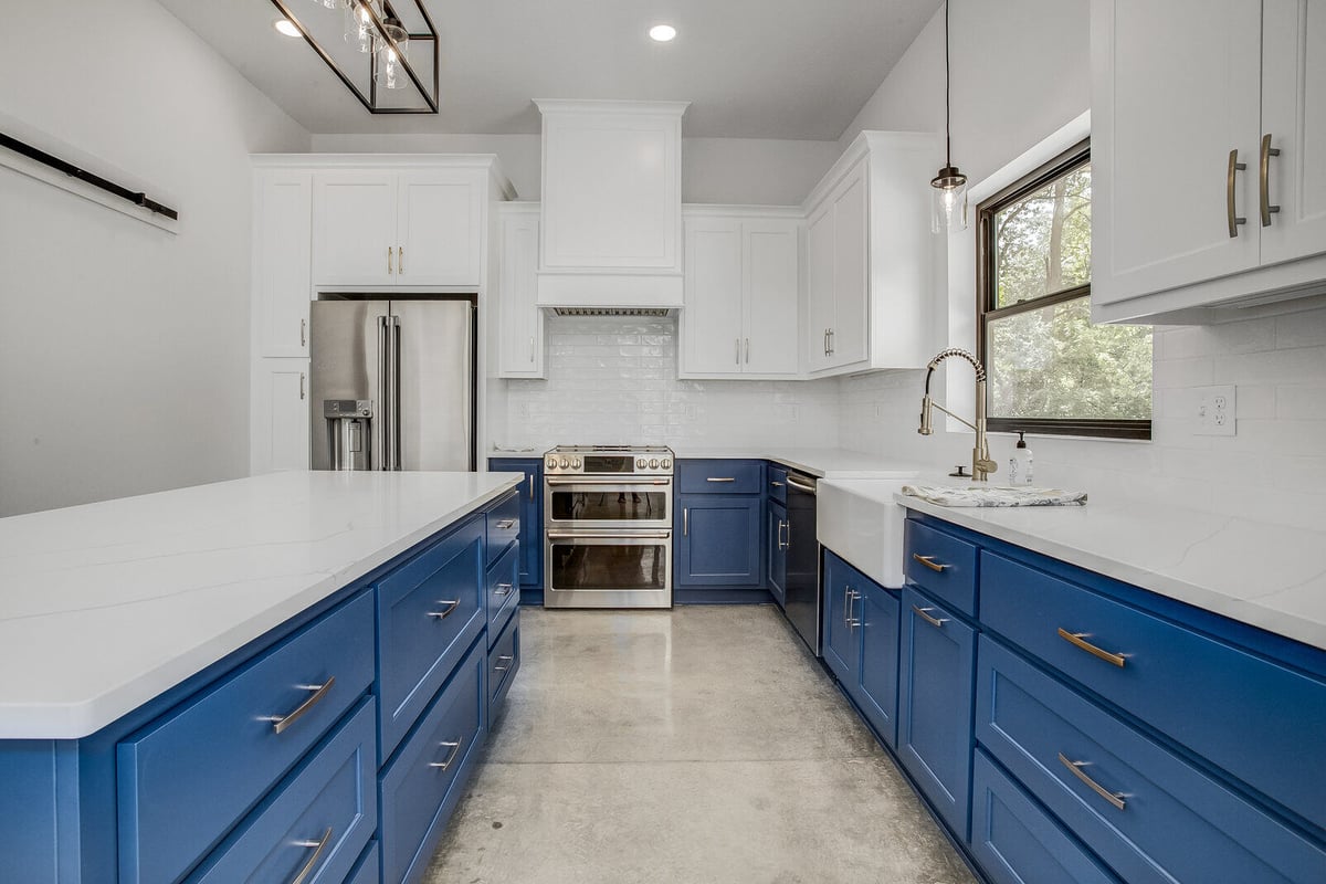 Sleek kitchen with a professional-grade range, navy blue cabinetry, and gold hardware, completed by Top Shelf Home Builders