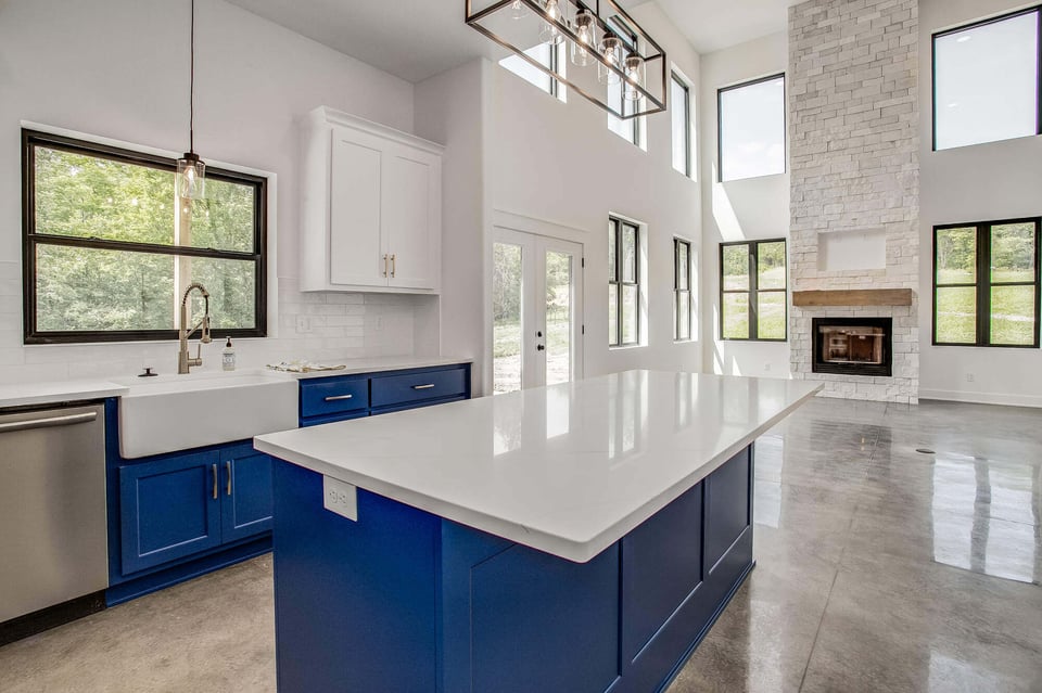 Open kitchen with a large island and white quartz countertop, overlooking a spacious living area with a stone fireplace, part of a Metro Kansas City remodel.jpg