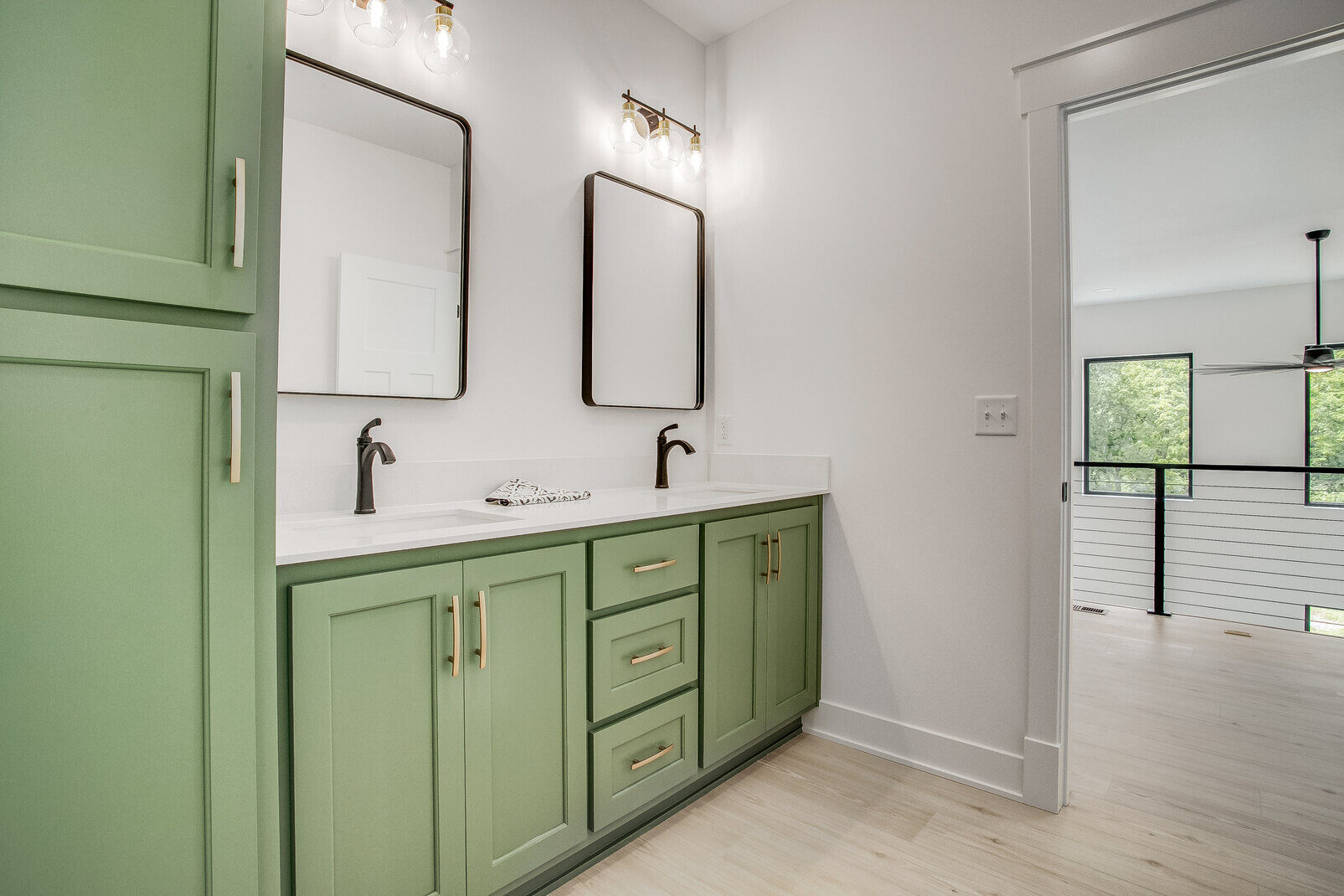 Custom-designed bathroom with a green vanity, gold hardware, and dual mirrors in a Metro Kansas City whole home remodel