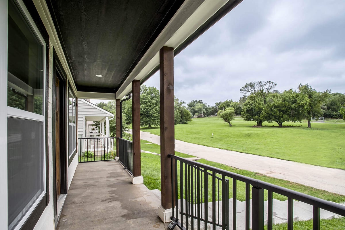 Covered front porch of a Kansas City home remodel by Top Shelf Home Builders, overlooking a scenic green space