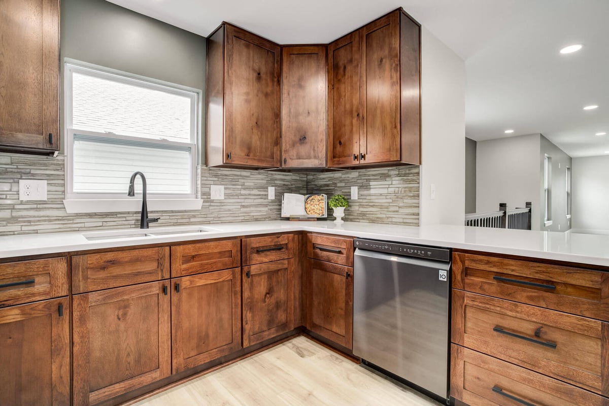 Cozy kitchen corner with a farmhouse-style sink, window, and warm wood cabinets in Burton remodel