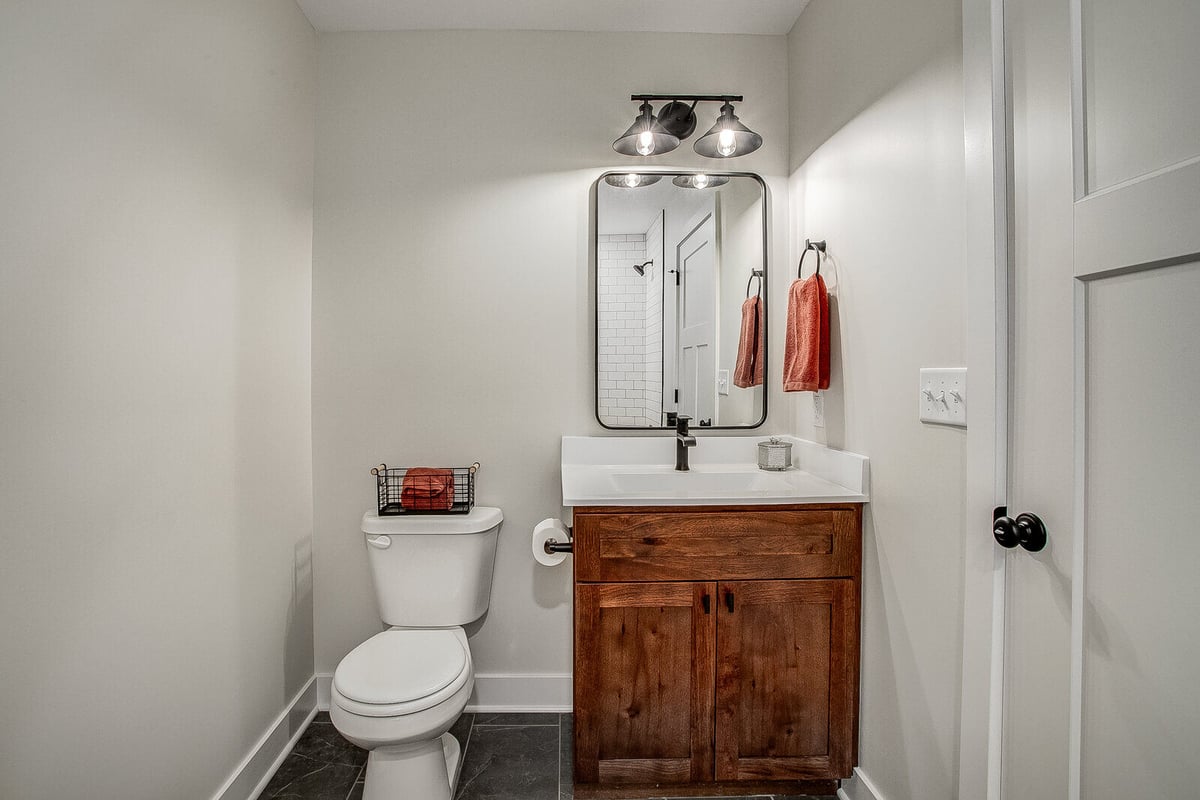 Guest bathroom with a single vanity, wood cabinetry, and stylish black fixtures, part of a Metro Kansas City home remodel by Top Shelf Home Builders.jpg