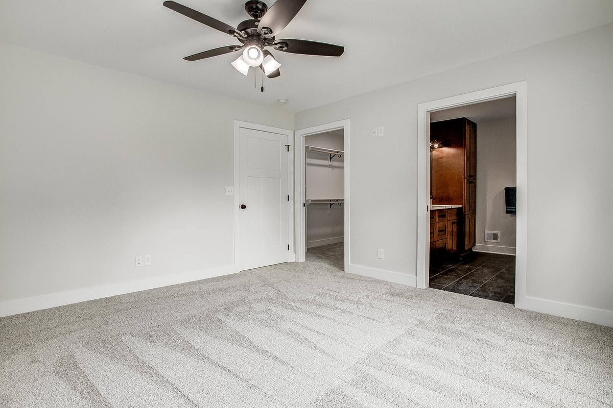 Master bedroom with dual entry to a walk-in closet and en-suite bathroom in a Metro Kansas City whole home remodel by Top Shelf Home Builders