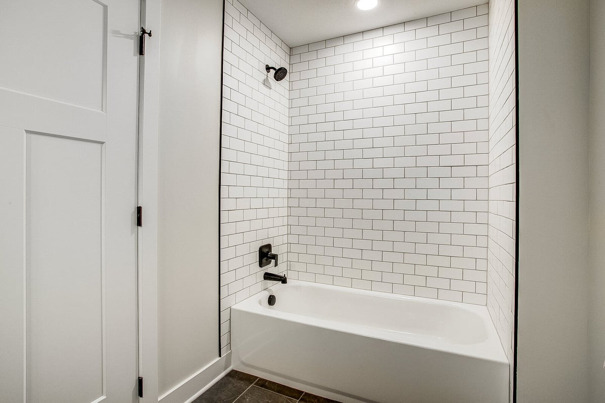 Modern bathroom with a white subway tile bathtub surround and black fixtures, part of a Metro Kansas City home remodel by Top Shelf Home Builders