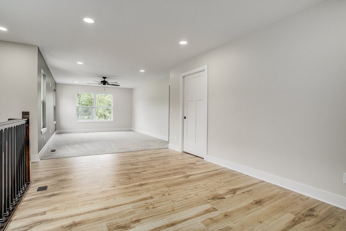 Open-concept living space with hardwood flooring, recessed lighting, and large windows in a Metro Kansas City home remodel by Top Shelf Home Builders.jpg