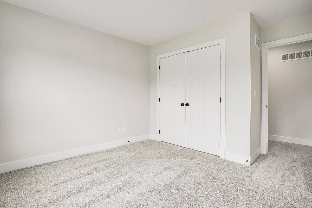 Secondary bedroom with neutral walls and plush carpeting, part of a Metro Kansas City home remodel by Top Shelf Home Builders