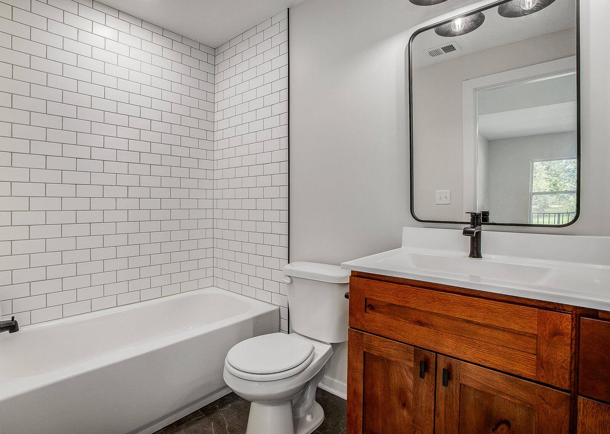 Stylish bathroom with subway tile bathtub surround, a wooden vanity, and black fixtures, part of a Metro Kansas City home remodel by Top Shelf Home Builders.jpg