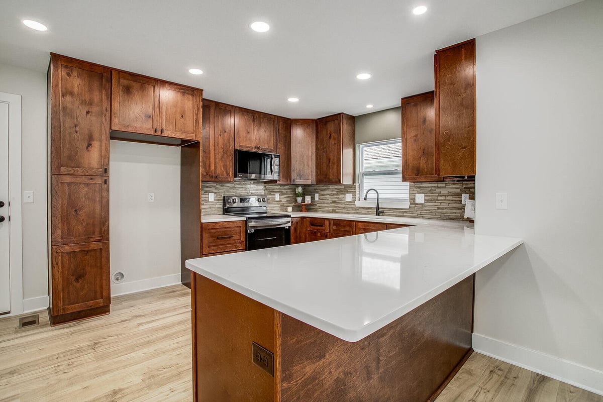 Stylish kitchen with warm wood cabinetry, a spacious island, and sleek countertops in Burton home remodel