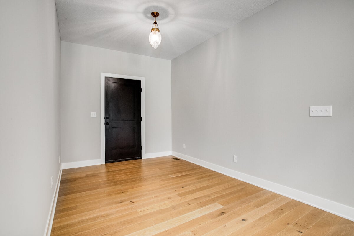 Bright entryway with light hardwood floors and a black door, part of a Kansas City whole home remodel by Top Shelf Home Builders