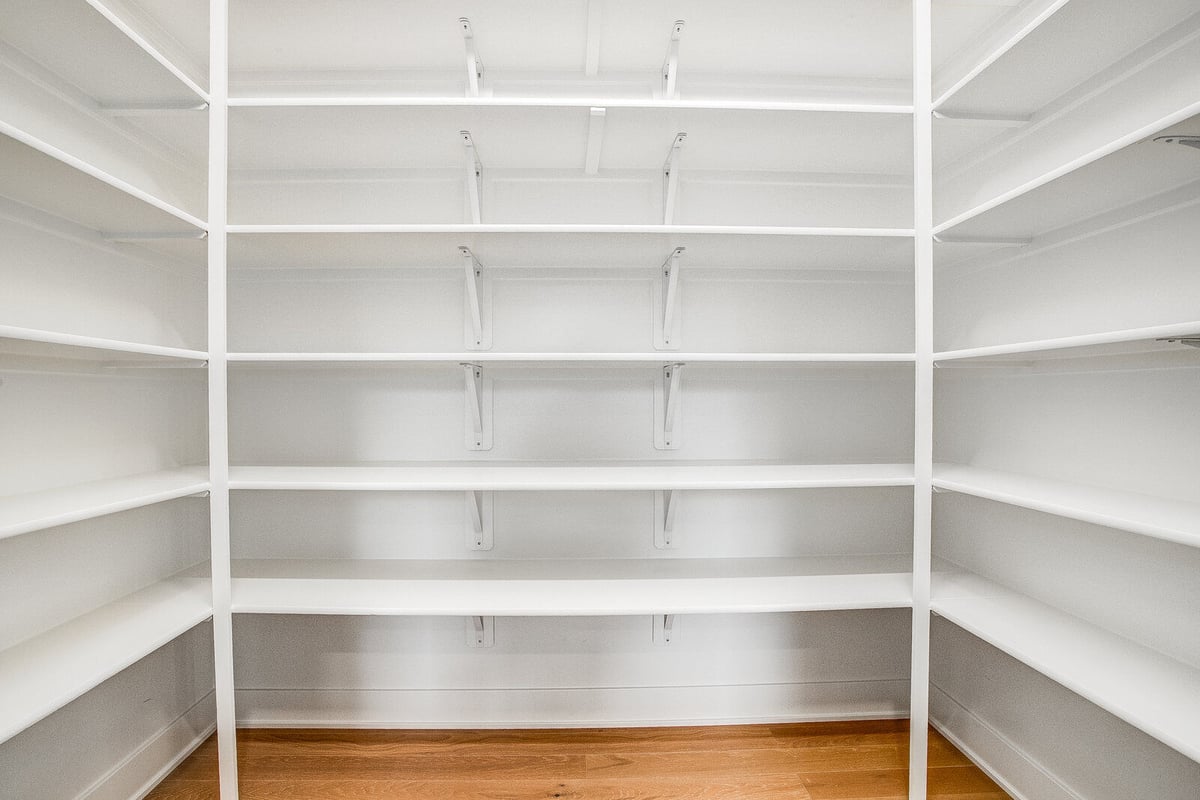 Custom-built walk-in pantry with white shelving and hardwood floors by Top Shelf Home Builders in Metro Kansas City