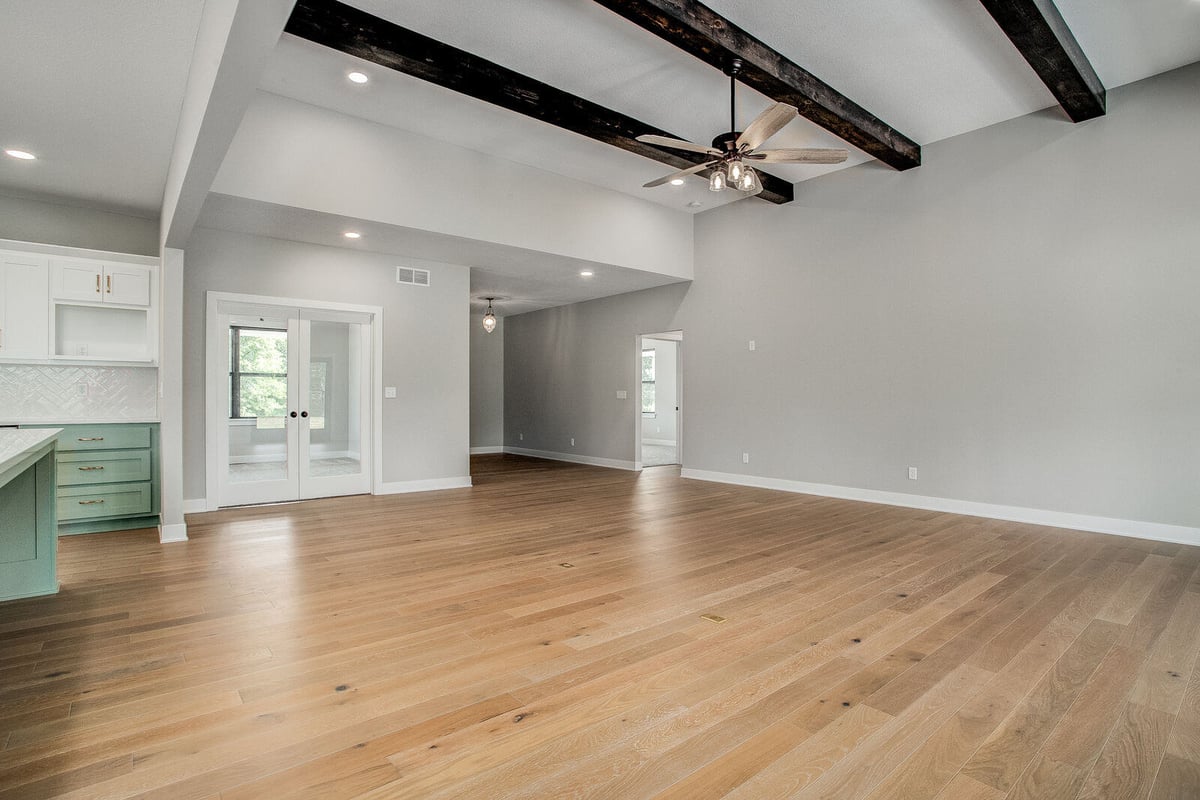 Luxury living space with high ceilings, dark wood beams, and an open floor plan, remodeled by Top Shelf Home Builders in Kansas City