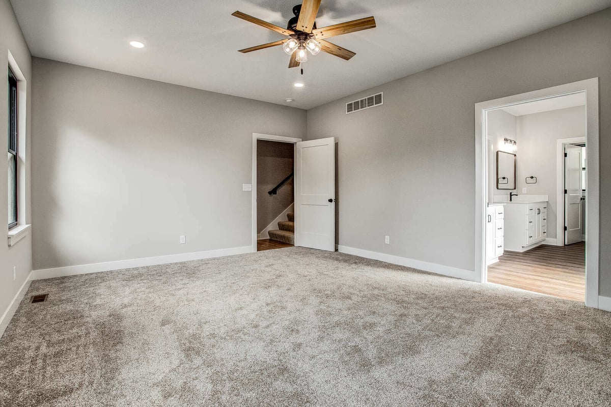 Master bedroom with an open doorway leading to an ensuite bathroom, part of a whole home remodel by Top Shelf Home Builders in Kansas City