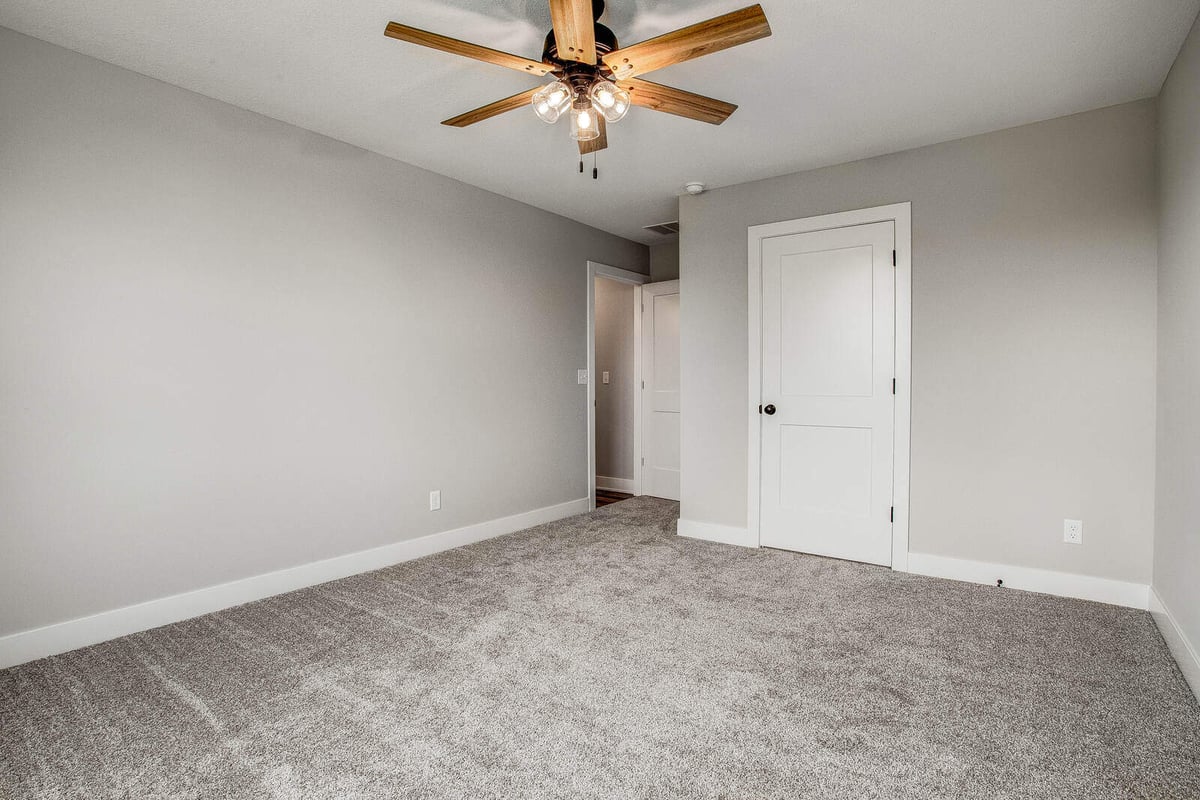 Minimalist bedroom with a modern ceiling fan and white doors, part of a whole home remodel by Top Shelf Home Builders in Kansas City