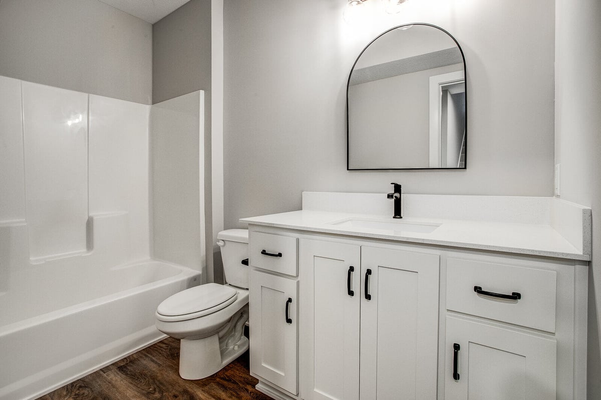 Modern bathroom remodel with white vanity, black hardware, and an arched mirror by Top Shelf Home Builders in Metro Kansas City