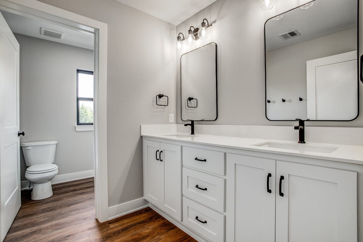 Modern bathroom renovation with dual vanities, black fixtures, and framed mirrors, completed by Top Shelf Home Builders in Kansas City