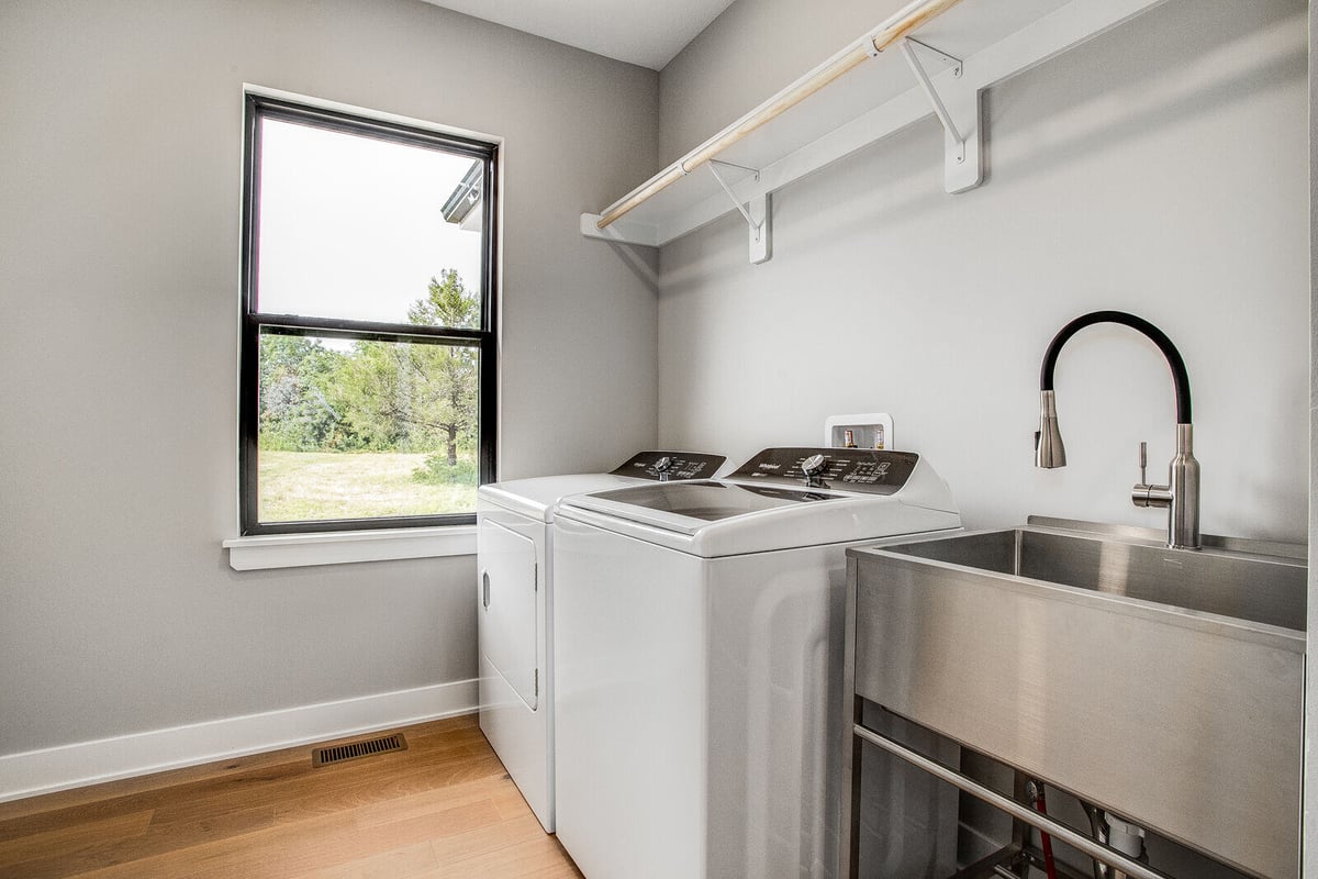 Modern laundry room remodel with stainless steel utility sink and large window by Top Shelf Home Builders in Metro Kansas City