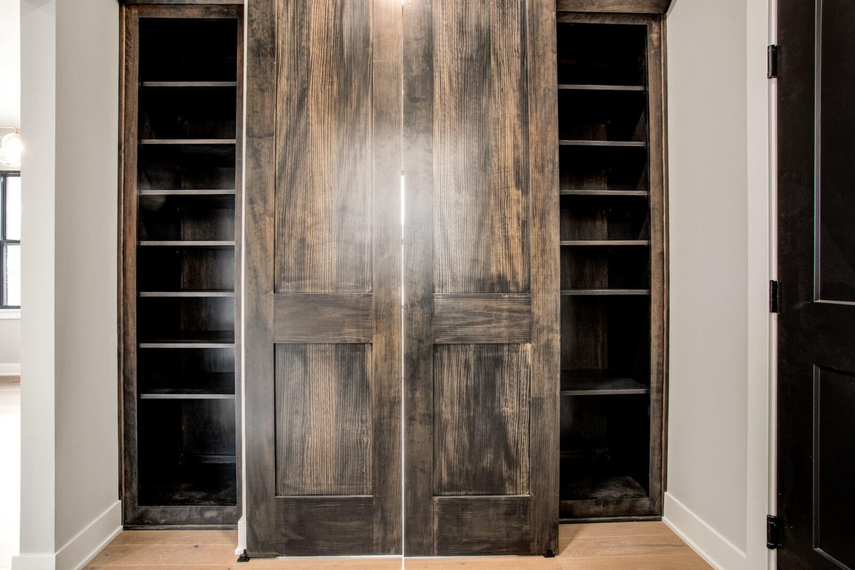 Rustic hidden storage closet with custom dark wood sliding doors, part of a whole home remodel in Metro Kansas City