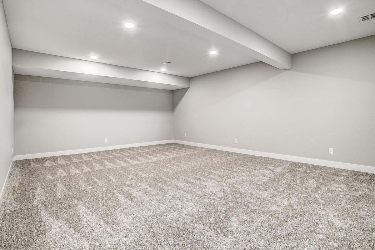 Spacious basement renovation with recessed lighting and plush carpeting by Top Shelf Home Builders in Metro Kansas City