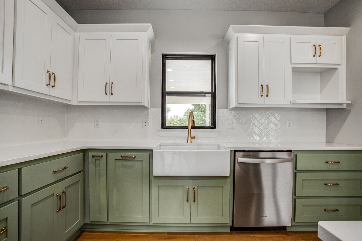 Stunning kitchen remodel with white and green cabinetry, farmhouse sink, and stainless steel dishwasher by Top Shelf Home Builders in Metro Kansas City.jpg