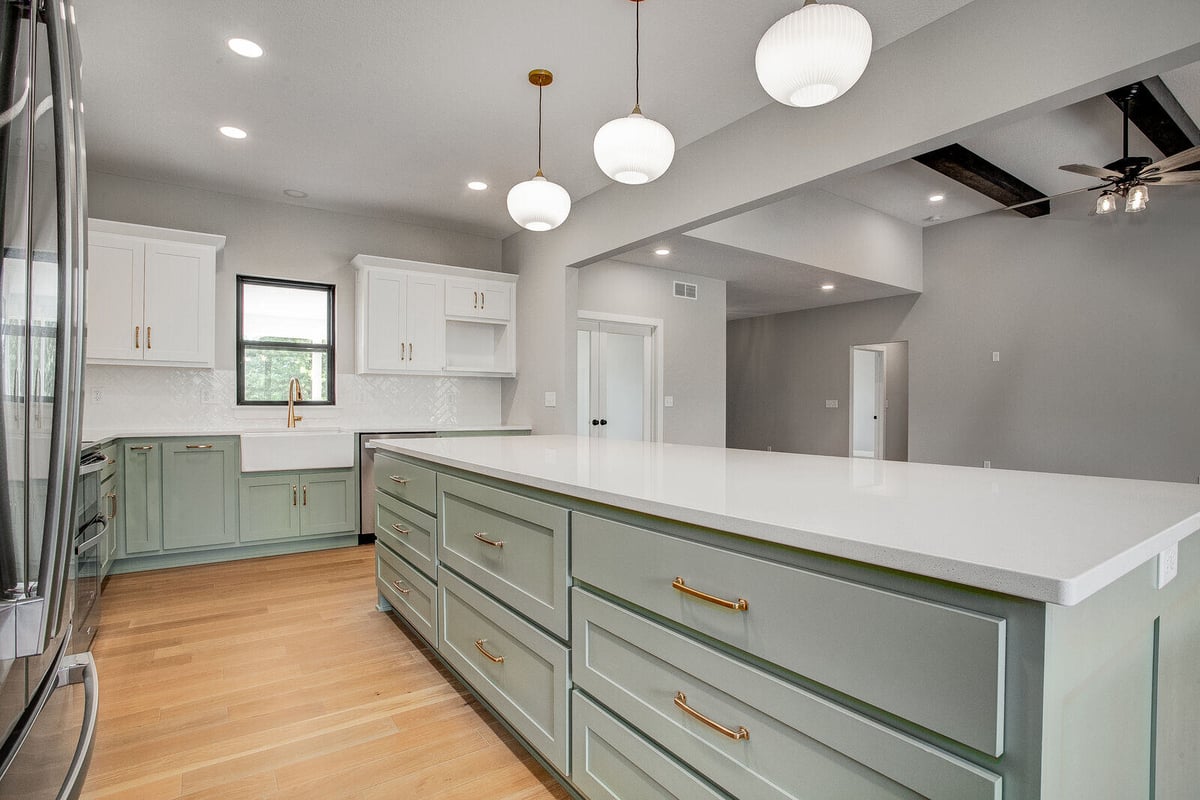 Stylish kitchen featuring sage green cabinets, white countertops, and gold fixtures, part of a Kansas City whole home remodel