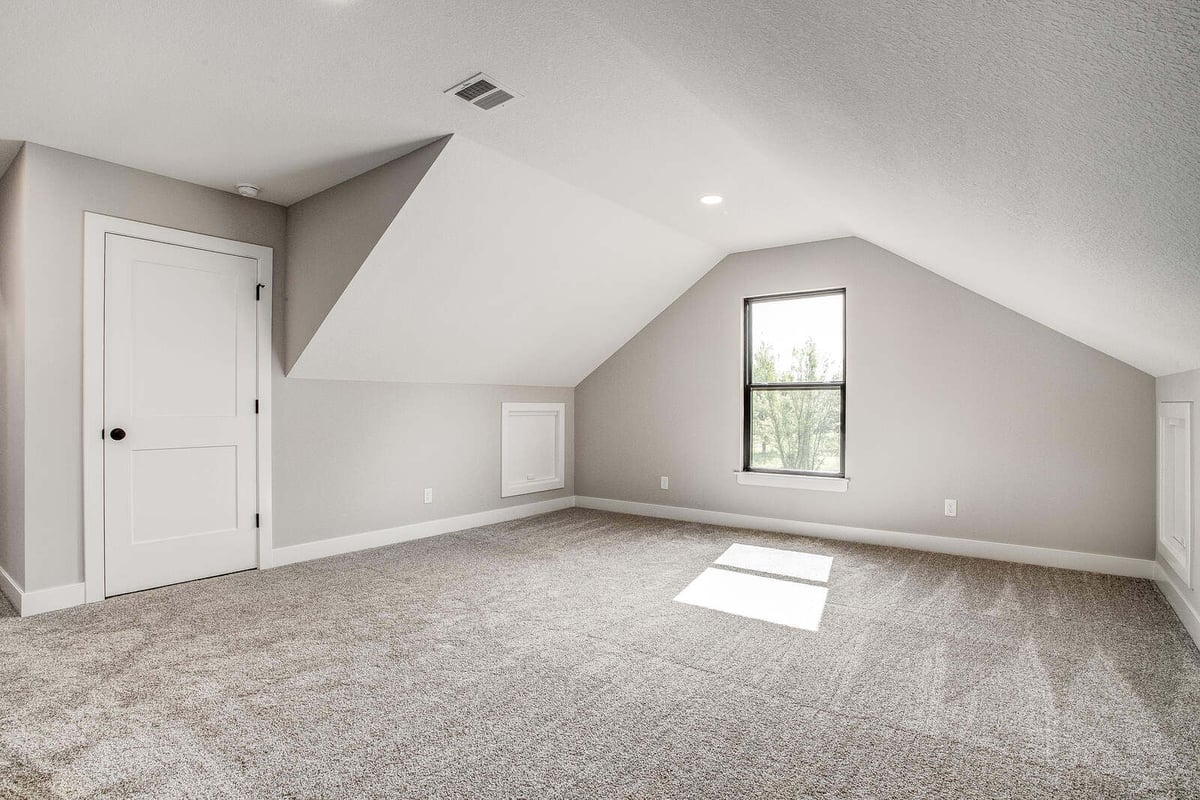 Upstairs loft or bonus room with sloped ceilings and neutral carpeting, part of a Kansas City home remodel by Top Shelf Home Builders