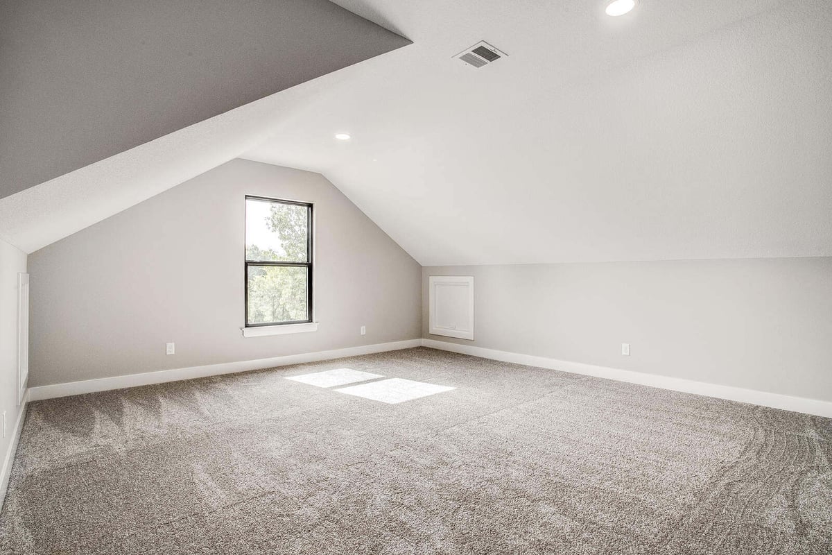 Upstairs loft with a contemporary design, featuring clean white walls and a bright window, remodeled by Top Shelf Home Builders in Kansas City
