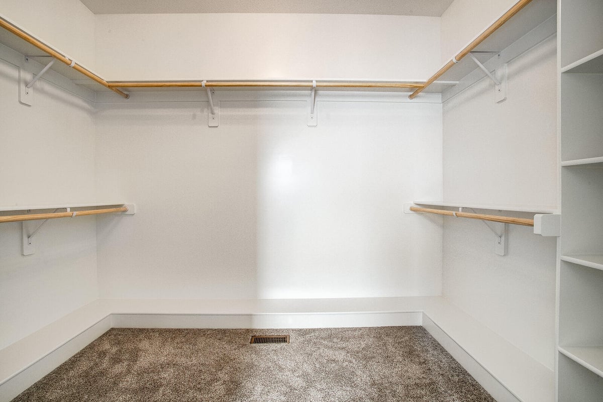 Walk-in closet with built-in storage and neutral carpeting, part of a Kansas City whole home remodel by Top Shelf Home Builders