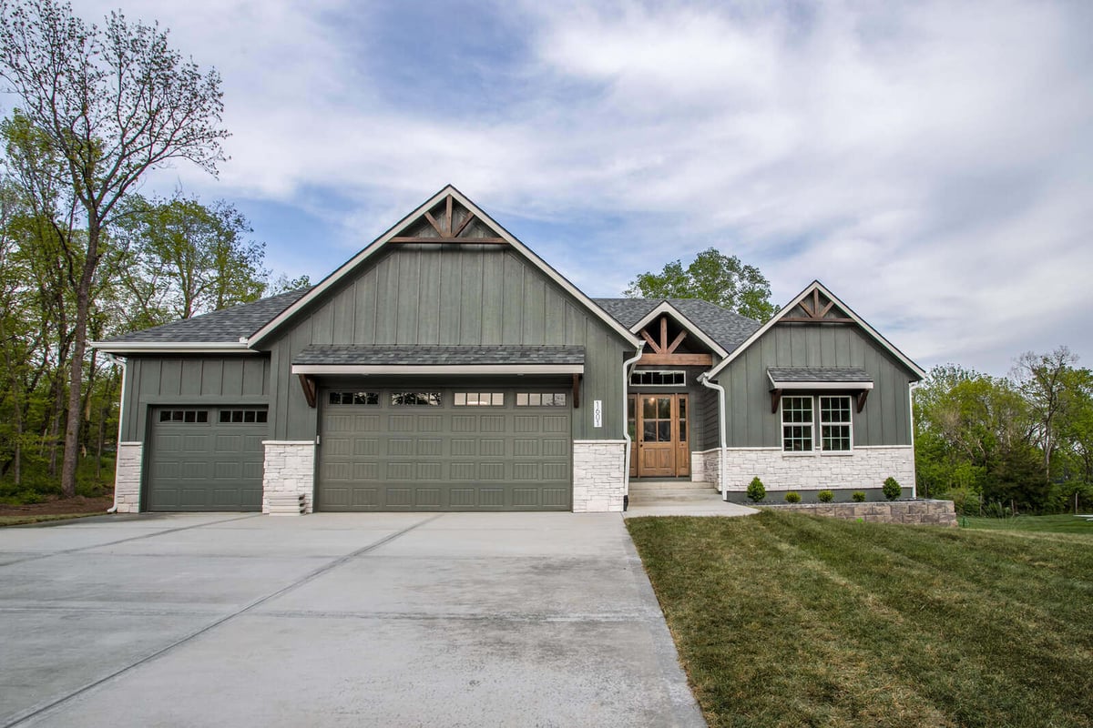 Angled front view of a remodeled home featuring green board and batten siding, white stonework, and wood accents in Metro Kansas City