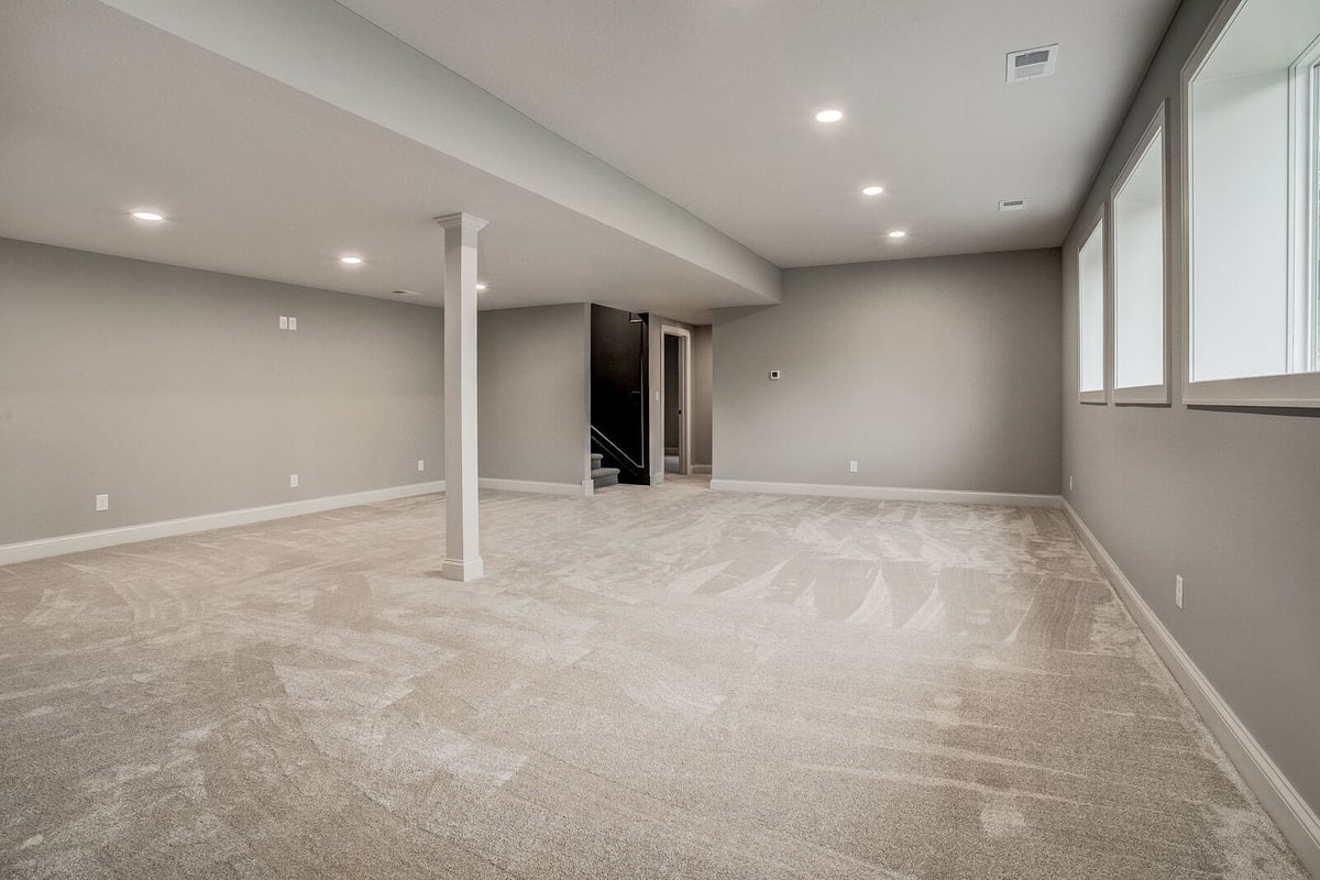 Bright basement with large windows, black double doors, and a wet bar in a Kansas City home remodel
